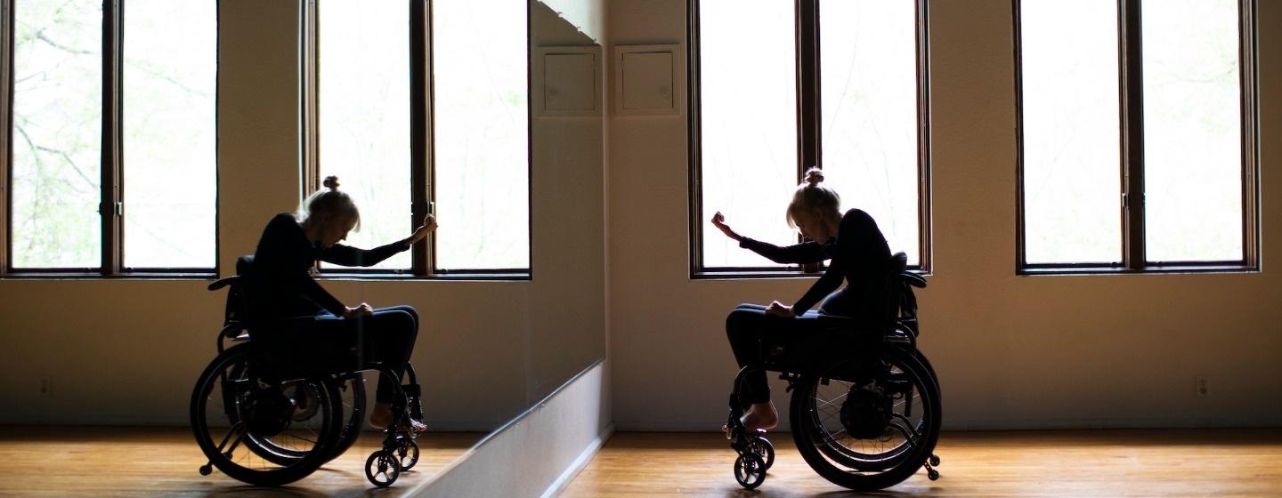 Kelsey Peterson is shown dancing in a studio while using her wheelchair.
